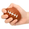 Balle anti stress en forme de ballon de rugby, pressée dans une main pour soulagement de la tension